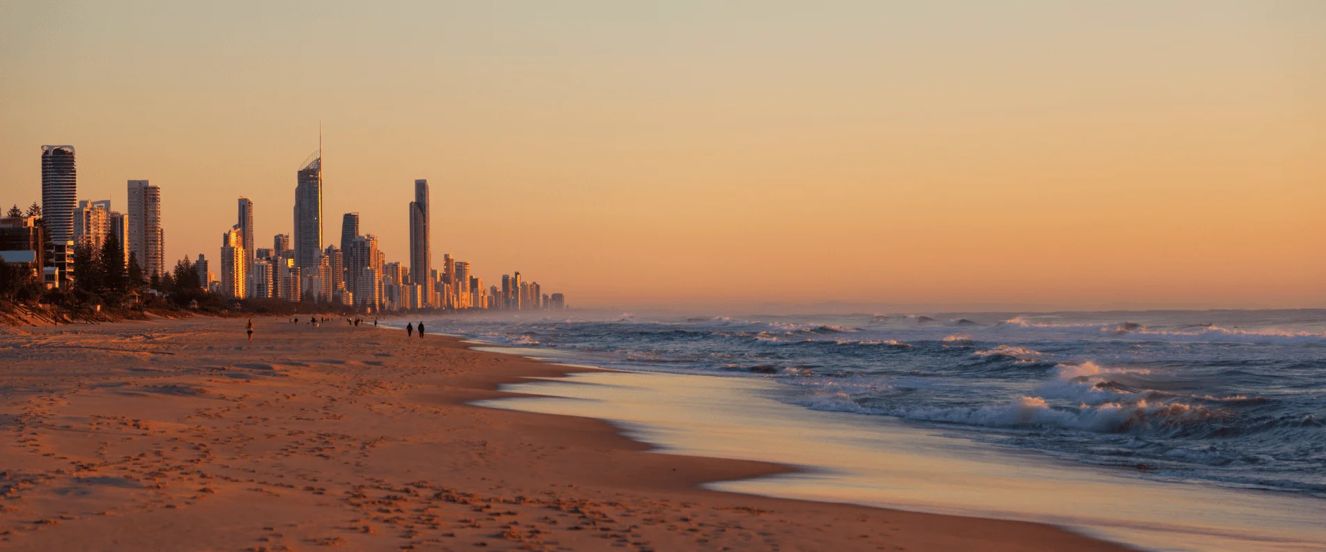 Sunset over the Gold Coast — golden sand, breaking waves and the Surfers Paradise skyline